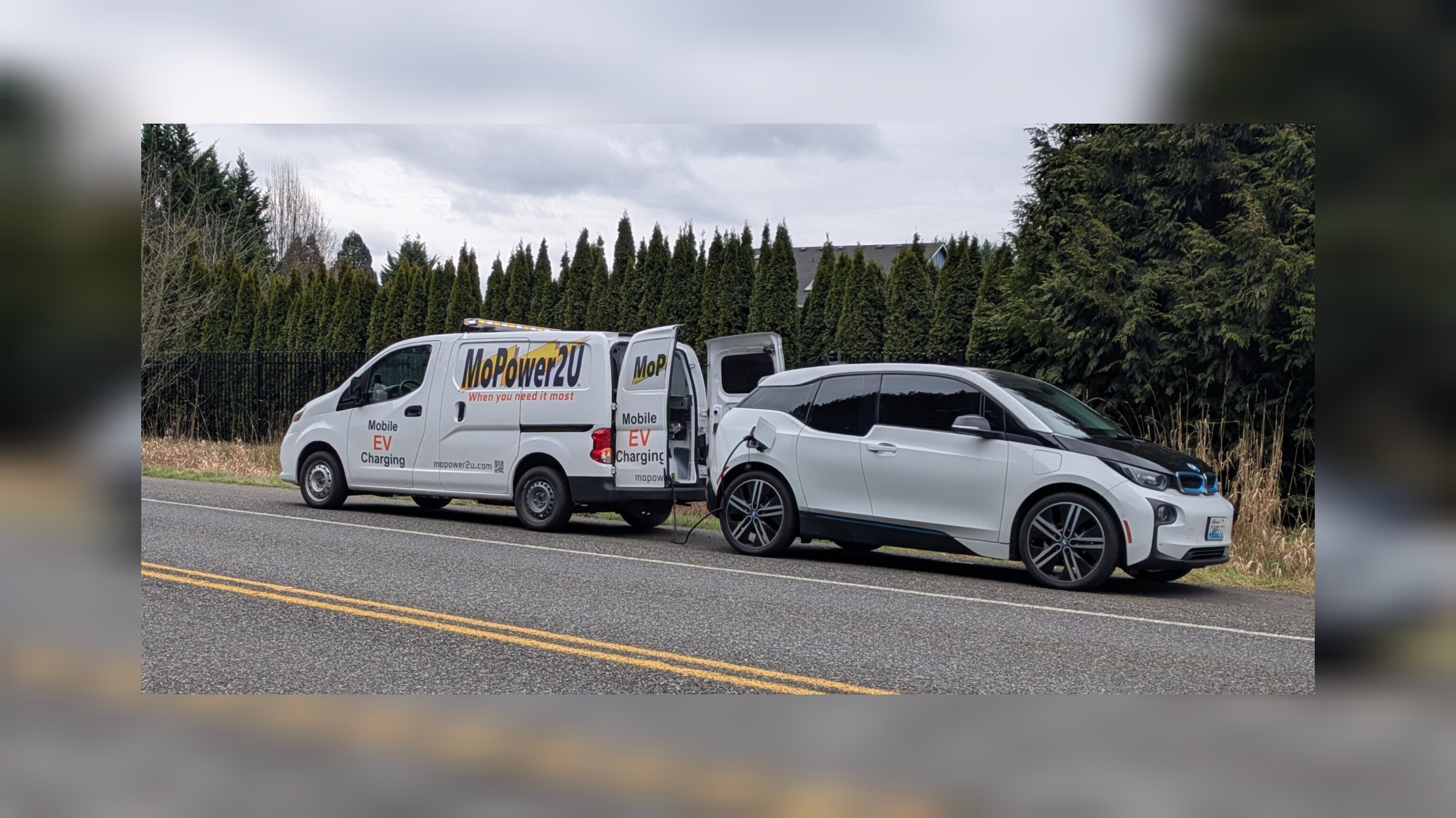 MoPower2U van charging a BMW i3 electric vehicle on a Pacific Northwest roadside